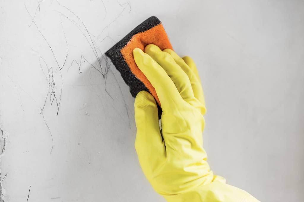 Cleaning a crayon drawing off a painted wall