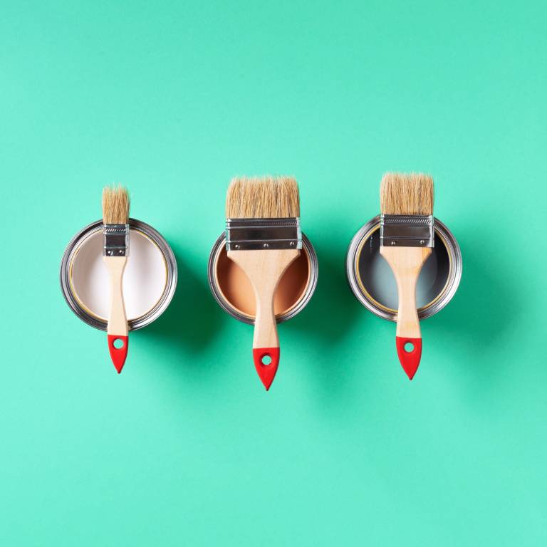 Paint brushes resting on colorful paint can lids